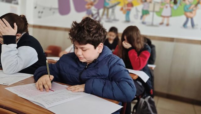 Sınıf ortamında odaklanarak ve konsantre olarak sınava giren bir grup çocuk.