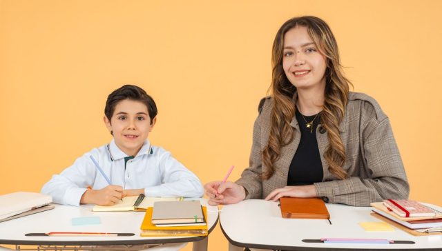 Bir öğretmen ve öğrenci okulda kitap ve notlarla birlikte çalışıyorlar.