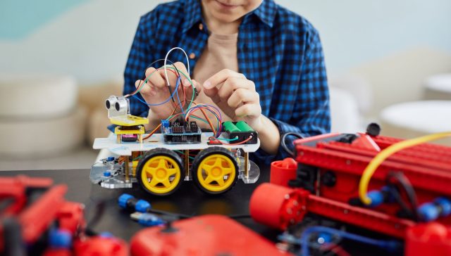 Young boy engaged in assembling a robotic toy car, showcasing early interest in STEM education.