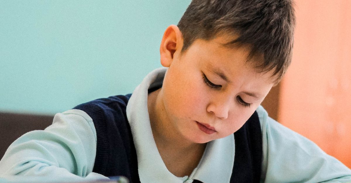 Bir çocuğun derslik ortamında titizlikle çalışması, konsantrasyon ve öğrenmeyi sergiliyor.