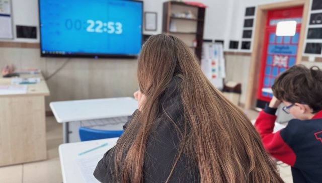 Ekranda dijital zamanlayıcı bulunan modern bir sınıfta konsantre olan öğrenciler.