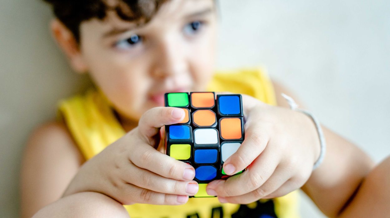 Young boy holding and concentrating on solving a colorful Rubik's Cube indoors.
