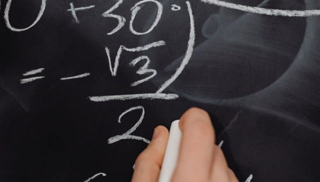 Bir sınıf ortamında kara tahtaya karmaşık matematik denklemleri el yazısıyla yazma.