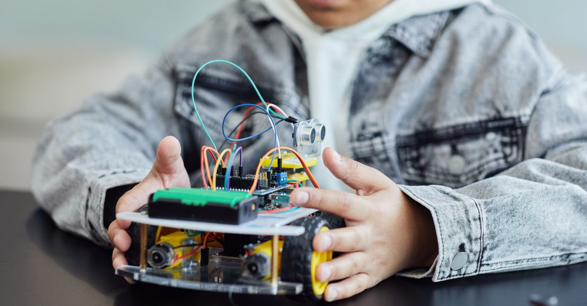 Bir çocuğun teller ve tekerleklerle DIY robotik projesi üzerinde çalışması, yenilik ve yaratıcılığı sergiliyor.
